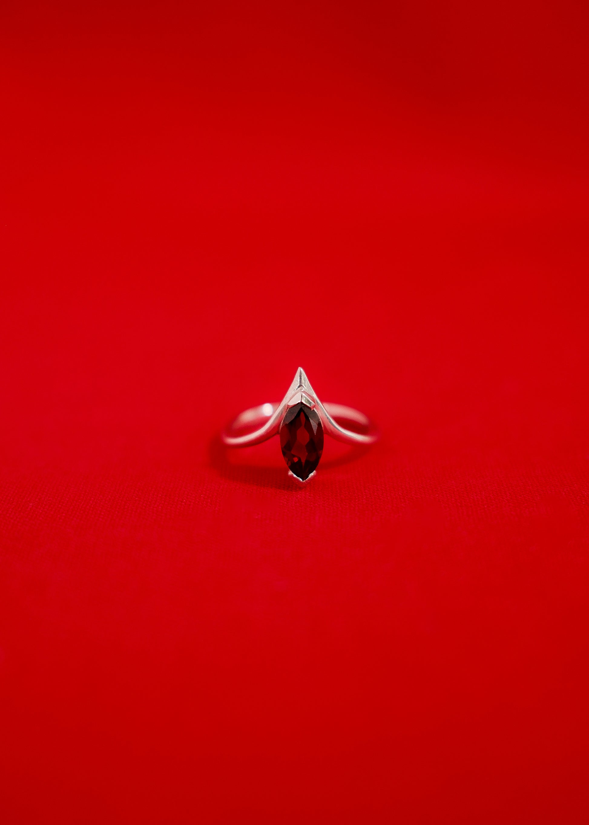 White gold ring with a garnet gemstone on a red background