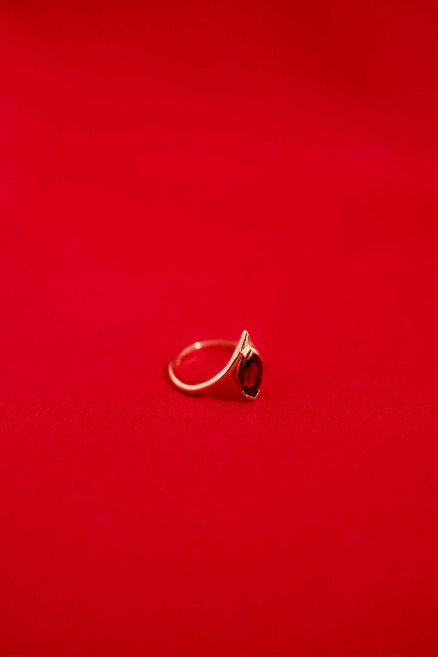 Gold ring with a garnet gemstone on a red background