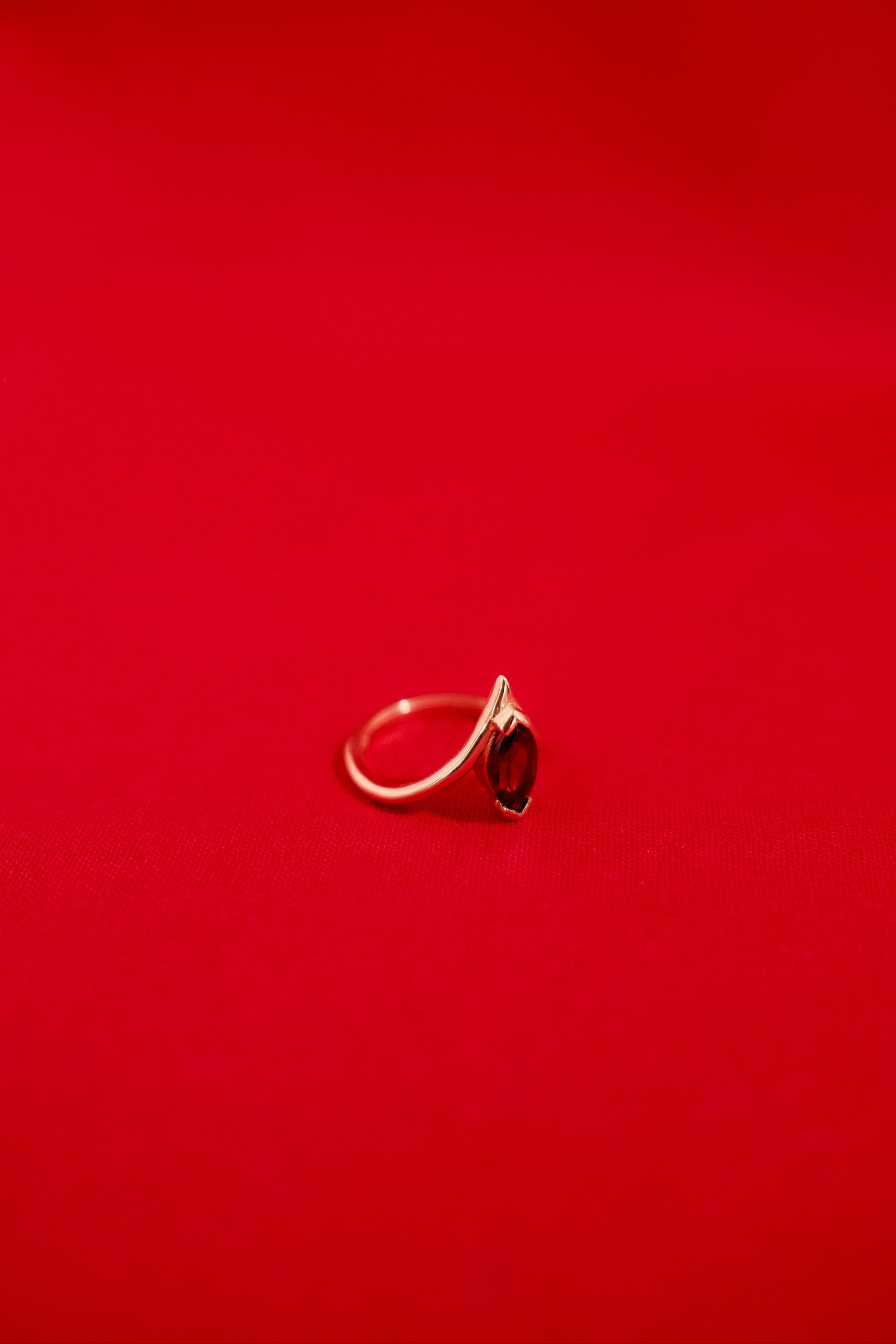 Gold ring with a garnet gemstone on a red background