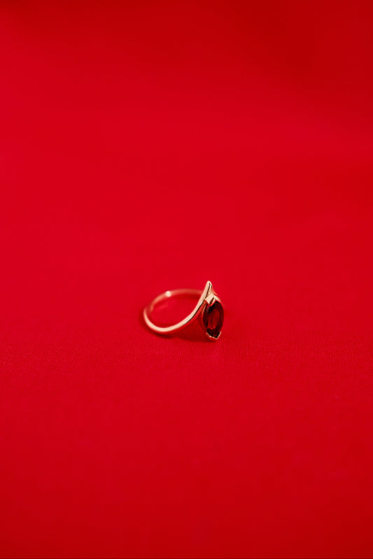 Gold ring with a garnet gemstone on a red background