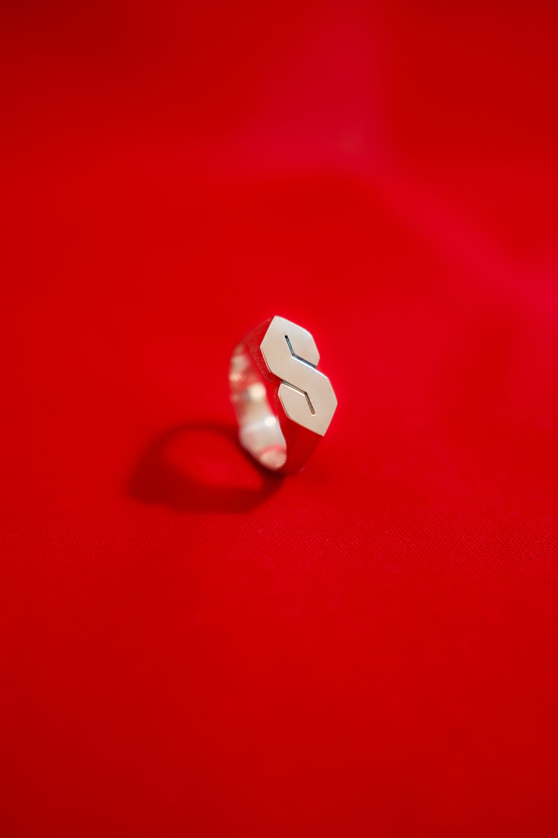 Silver signet style ring with the stussy 'S' on a red background