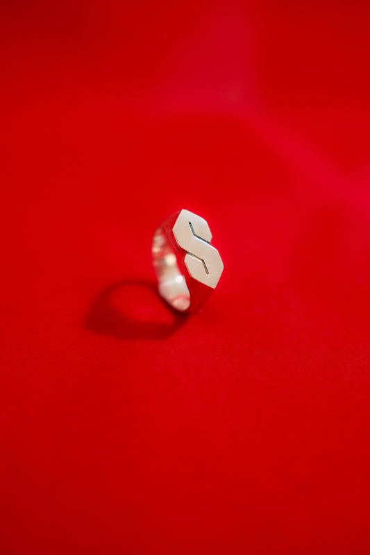 Silver signet style ring with the stussy 'S' on a red background