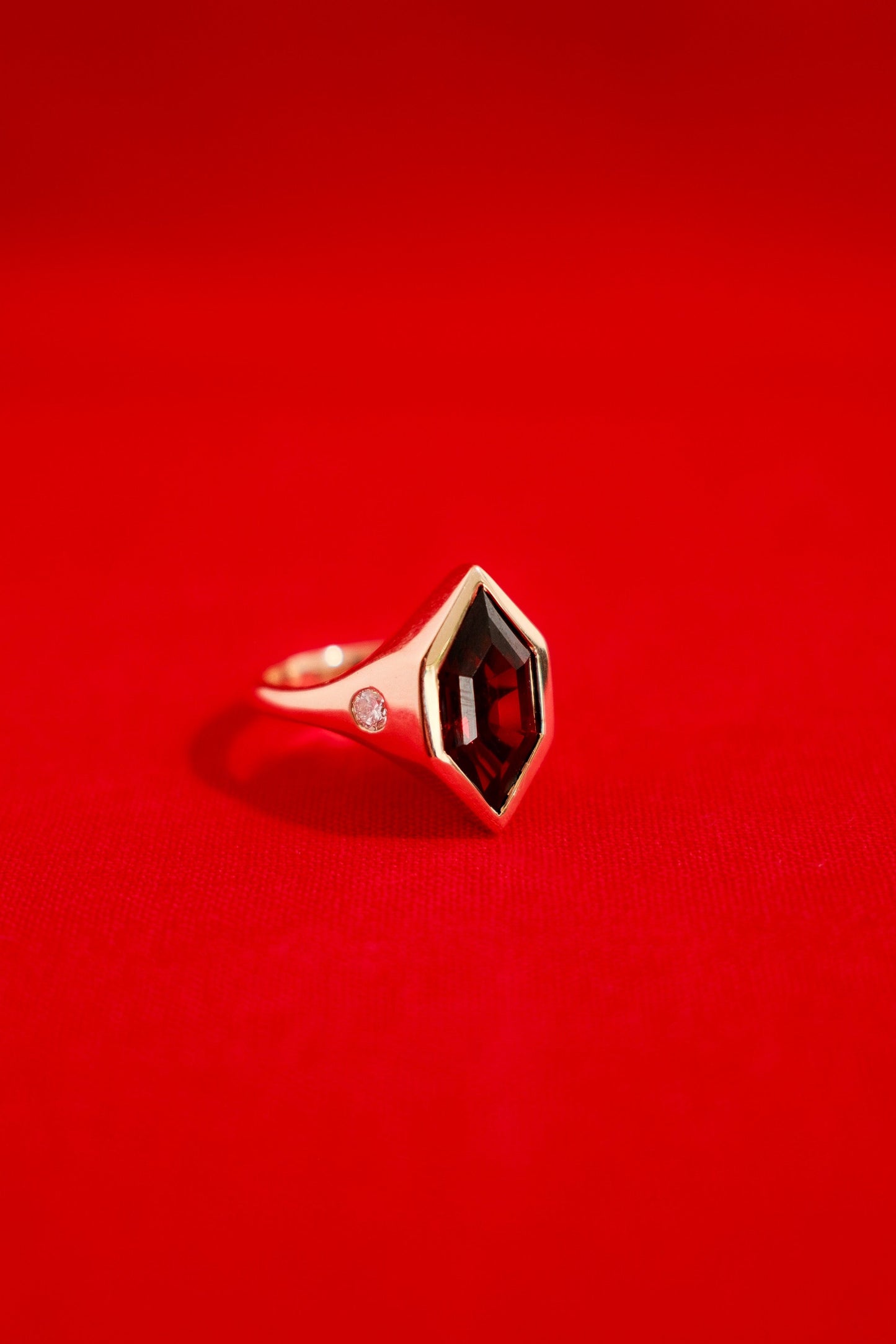 00Chunky solid gold ring with a garnet gemstone on a red background