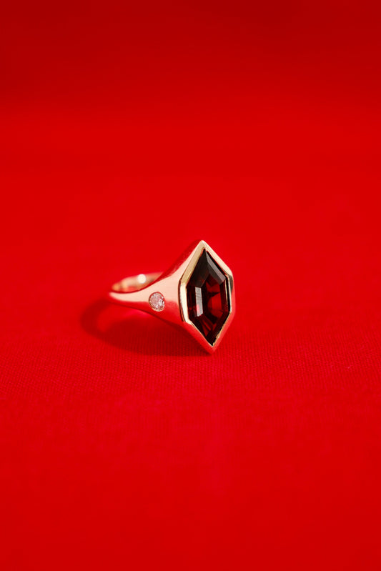 00Chunky solid gold ring with a garnet gemstone on a red background