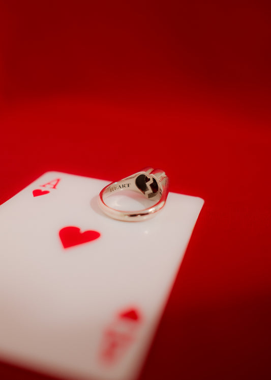 White gold ring with a broken heart design on a red playing card with hearts