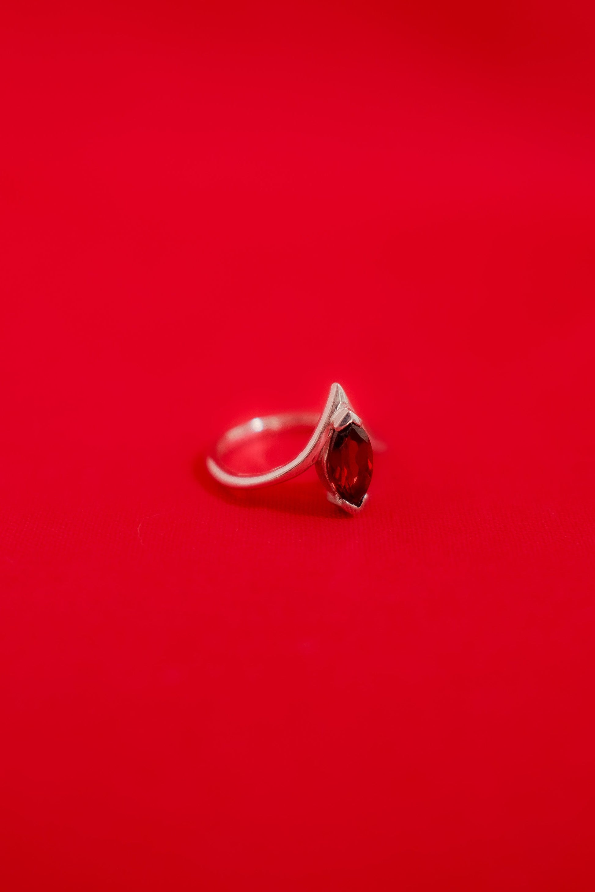 White gold ring with a garnet gemstone on a red background