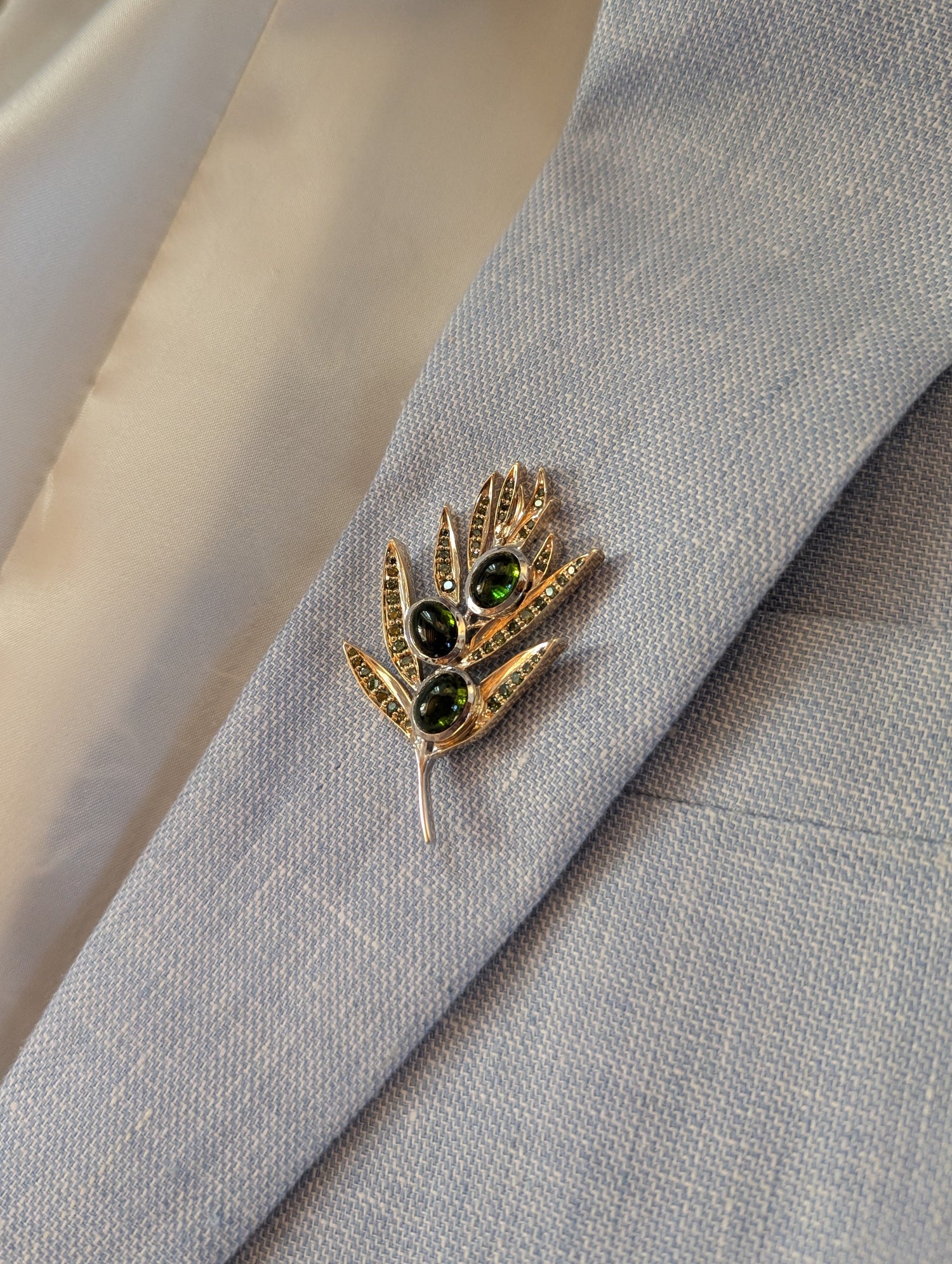 Olive branch brooch set with gemstones on a suit jacket